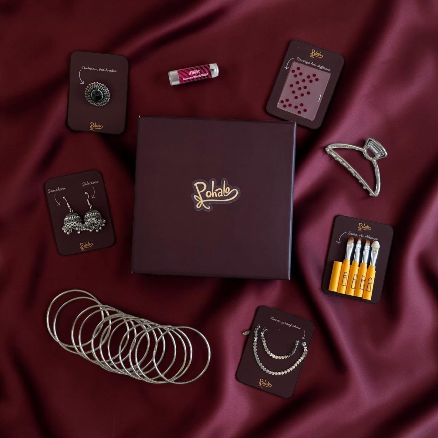 Collection of jewelry and accessories on a maroon fabric background with 'Poketo' branding.