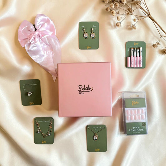 Collection of jewellery and beauty products on a satin surface with Pohalo branding. Set of 7 products