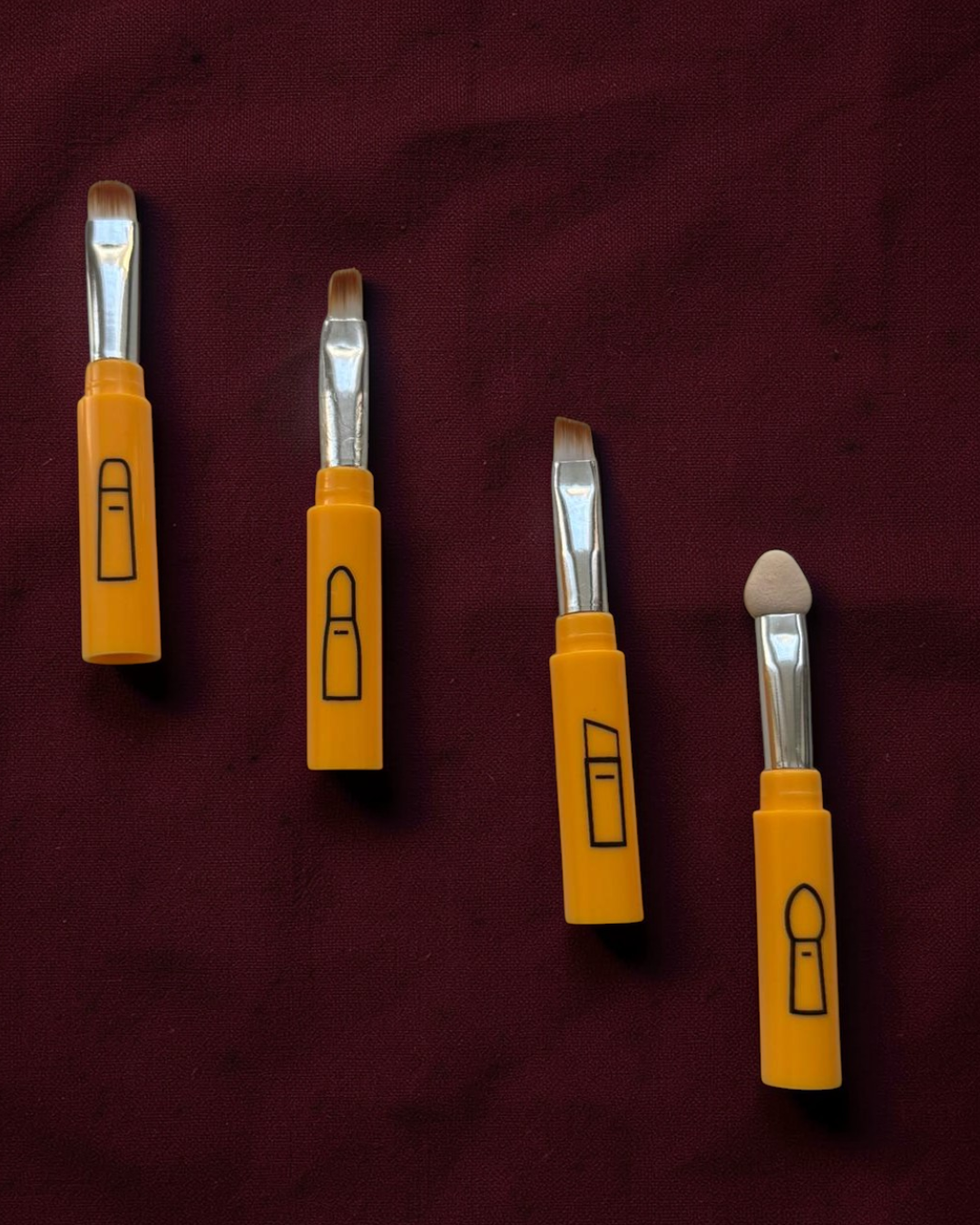 Four yellow-handled tools with metal heads on a maroon background