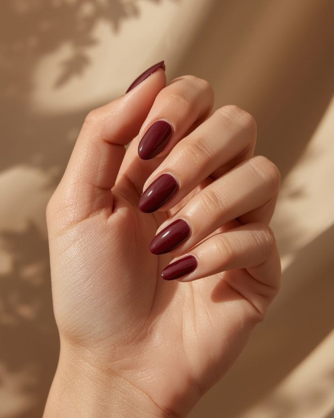 Hand with dark red nail press on nails  on a neutral background