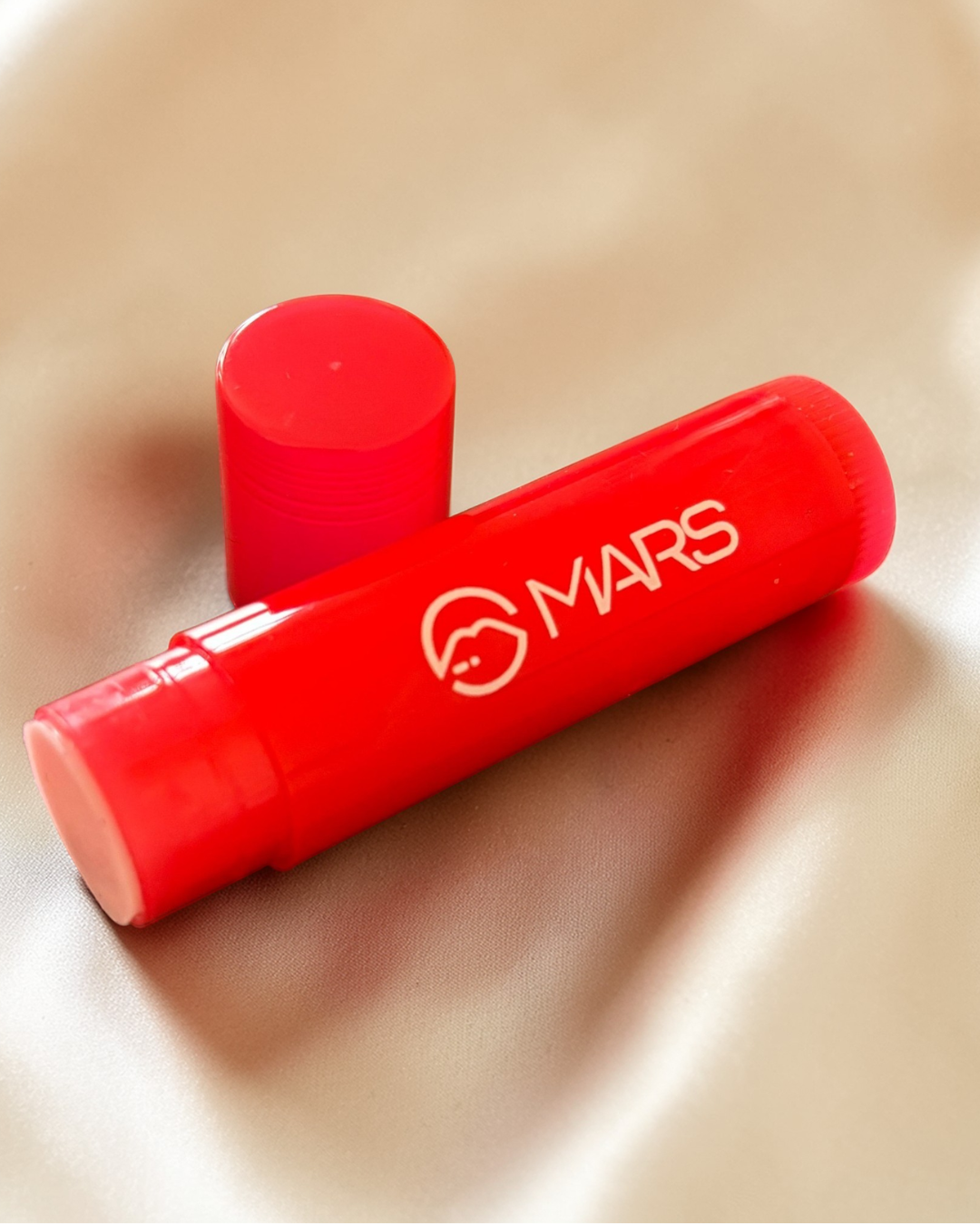 Red Mars lip balm on a beige surface